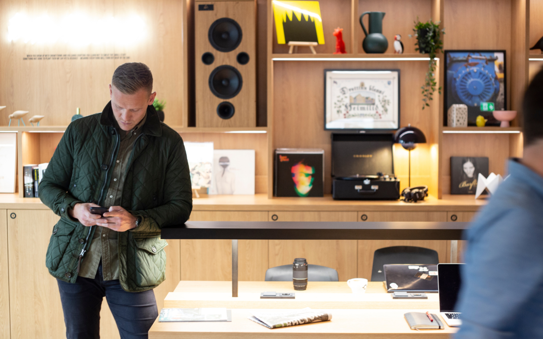 Guest using phone at stylish communal workspace with vinyl records and Scandinavian design at Center Hotels Laugavegur in Reykjavik.