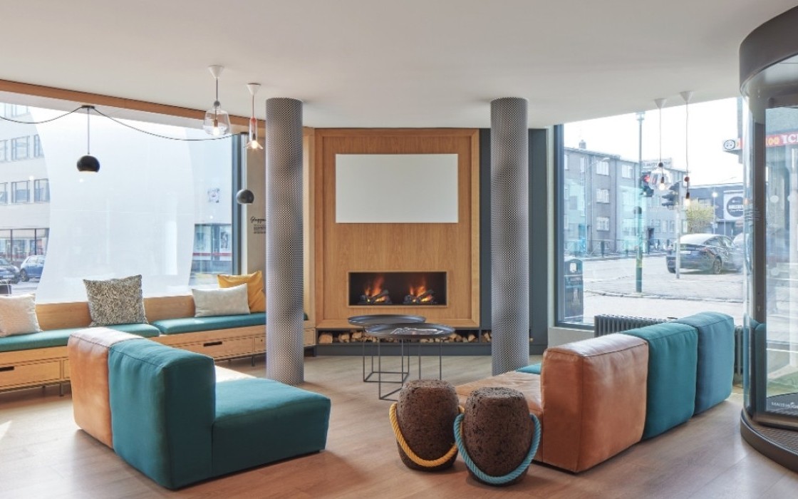 Hotel lounge at Center Hotels Laugavegur in Reykjavik. Includes colorful seating, large street facing windows, and a fireplace.