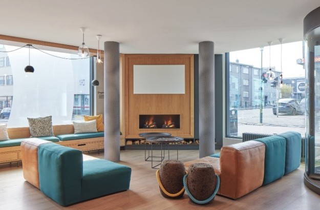 Hotel lounge at Center Hotels Laugavegur in Reykjavik. Includes colorful seating, large street facing windows, and a fireplace.