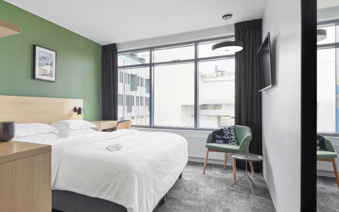 Standard room at Center Hotels Laugavegur featuring a large bed, green accent wall, large windows and green chairs.