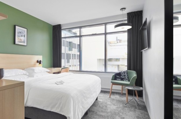 Standard room at Center Hotels Laugavegur featuring a large bed, green accent wall, large windows and green chairs.