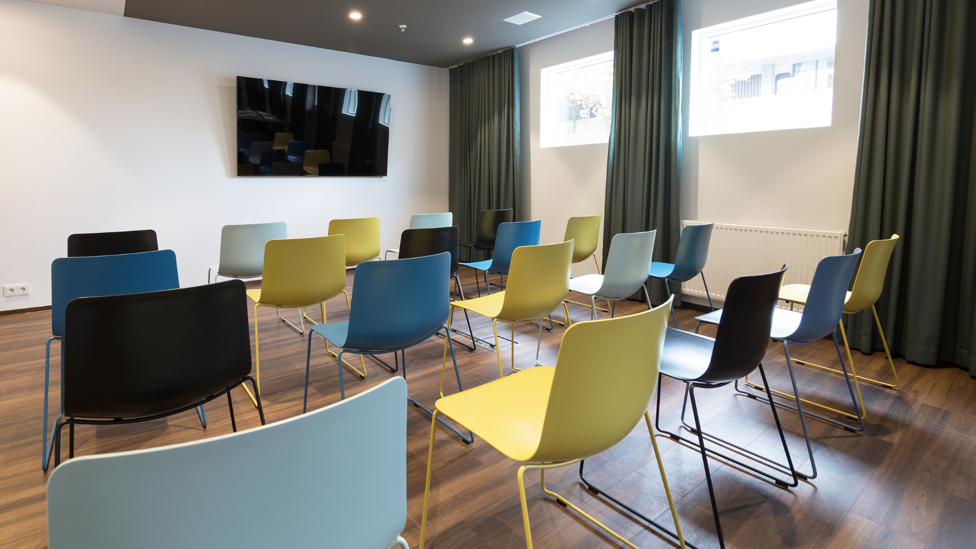 Colorful chairs arranged in rows facing a screen in Gardur meeting room at Midgardur by Center Hotels in Reykjavik.