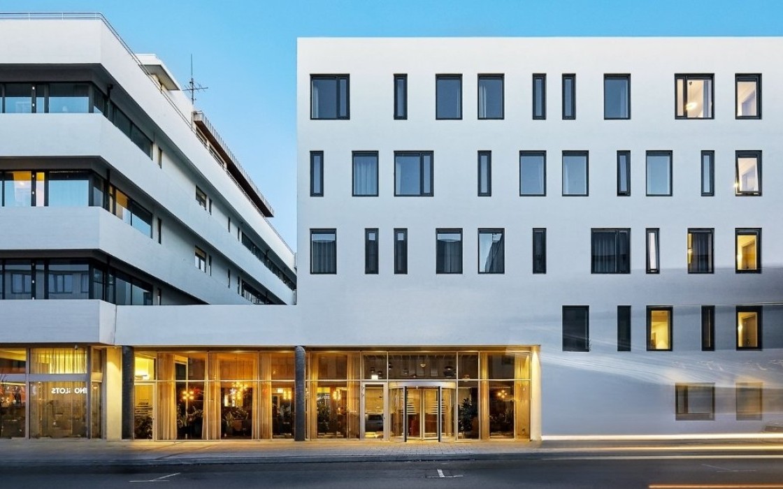 Exterior of Midgardur by Center Hotels in central Reykjavik, with warm interior lighting visible through the lobby windows.
