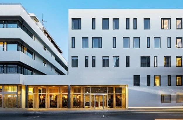 Exterior of Midgardur by Center Hotels in central Reykjavik, with warm interior lighting visible through the lobby windows.