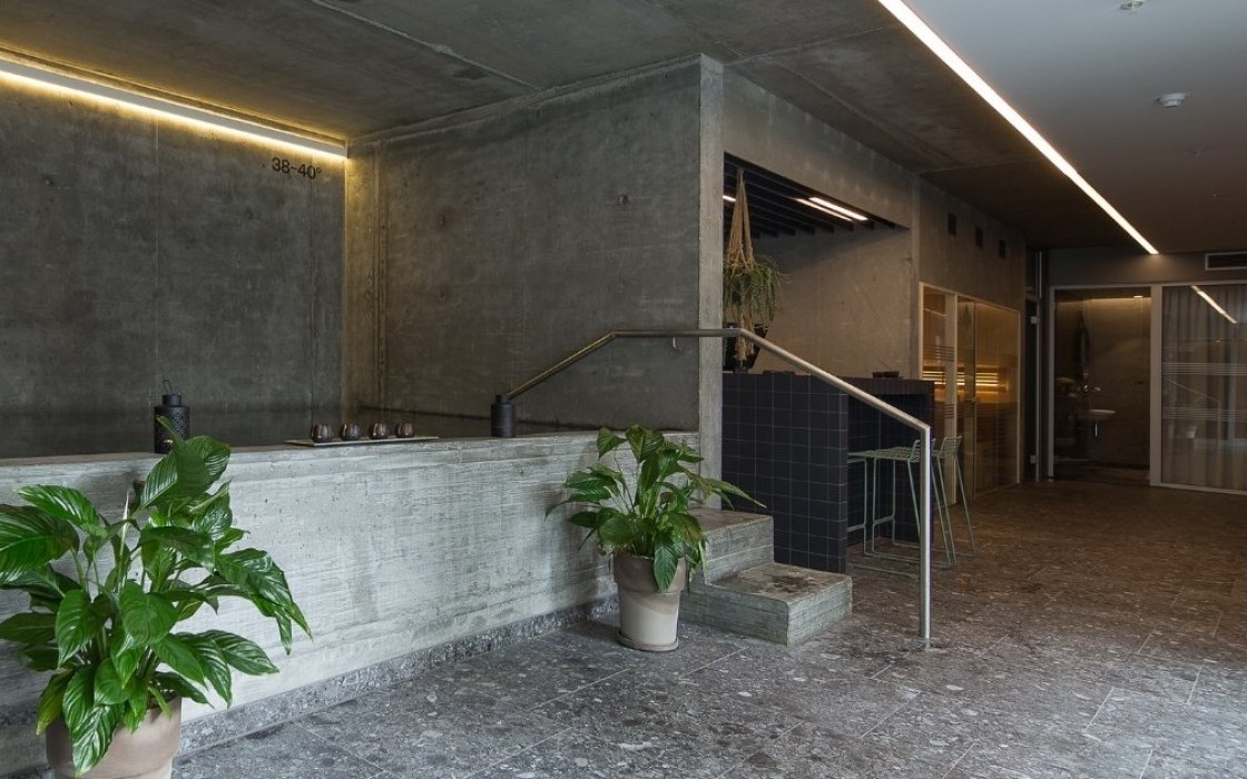 Stylish spa interior at Midgardur with indoor hot tub, lounge seating, and potted plants.