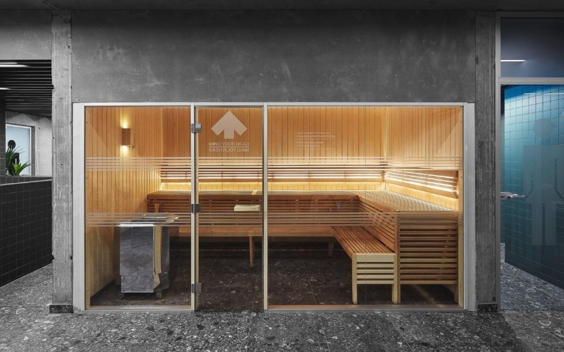 Spacious glass-fronted sauna with warm wooden interior at Midgardur spa in Reykjavik center.