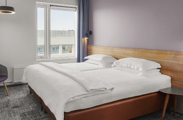 Full view of the standard room at Midgardur by Center Hotels in Reykjavik with a double bed, seating area, and a window with urban view.
