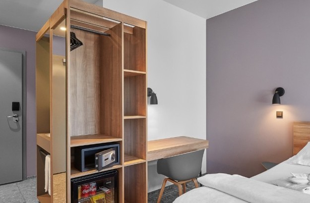 Interior of a standard plus room at Midgardur by Center Hotels in Reykjavik, with open shelving, a work desk, and soft lighting above the bed.
