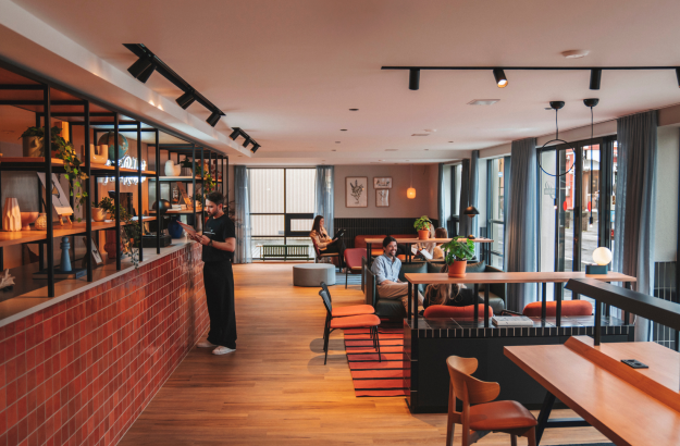 A modern lobby lounge at Center Hotels Plaza in Reykjavik, featuring warm wood flooring, comfortable seating with people relaxing, and large windows letting in natural light from the street o