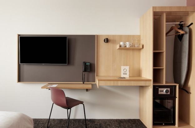 Interior of a Superior Room at Center Hotels Plaza in Reykjavík, showing a sleek and functional workspace with a wall-mounted TV, phone, writing desk, and open wardrobe area with a safe, mini