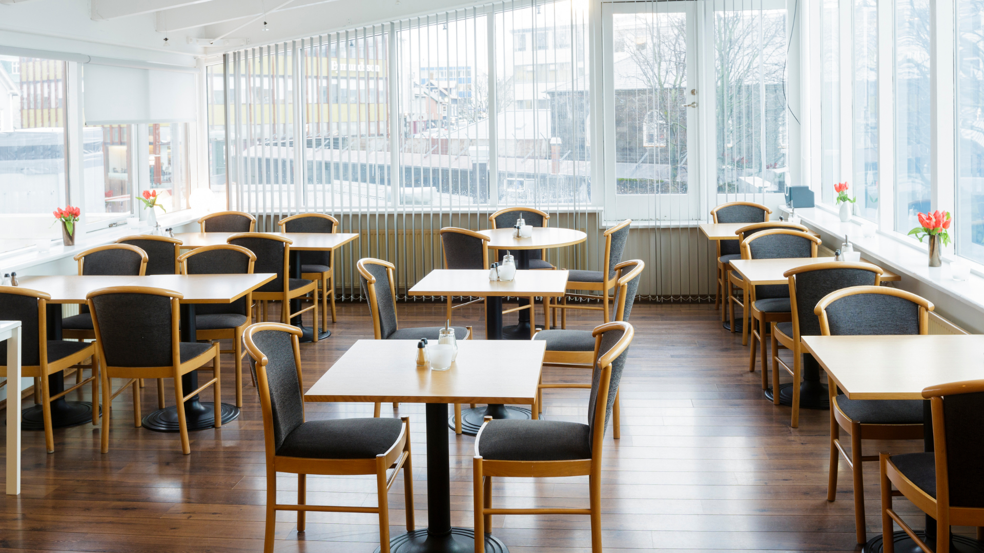 Bright breakfast area at Center Hotels Skjaldbreid in Reykjavik, with wooden floors, modern seating, and large windows offering city views.