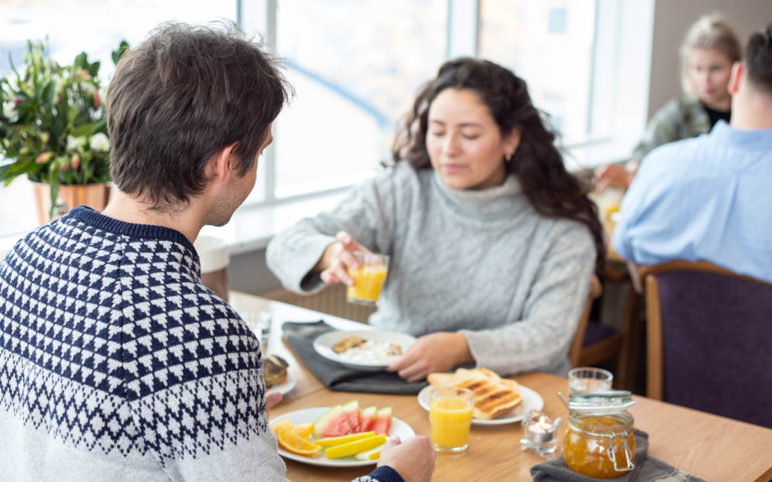 Guests enjoying breakfast at Center Hotels Skjaldbreid in Reykjavik, with fresh fruit, toast, juice, and natural light from large windows.