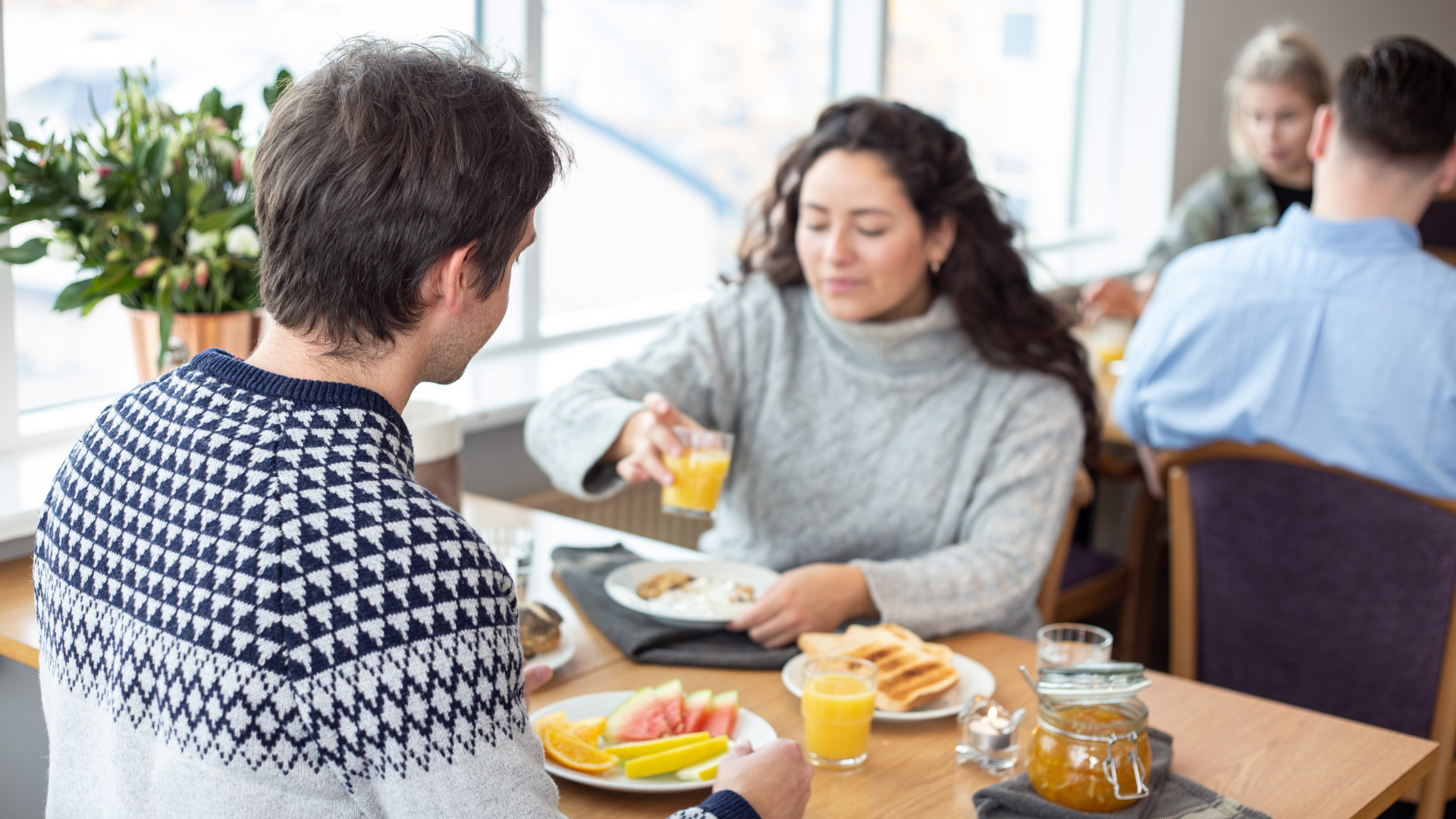 Guests enjoying breakfast at Center Hotels Skjaldbreid in Reykjavik, with fresh fruit, toast, juice, and natural light from large windows.