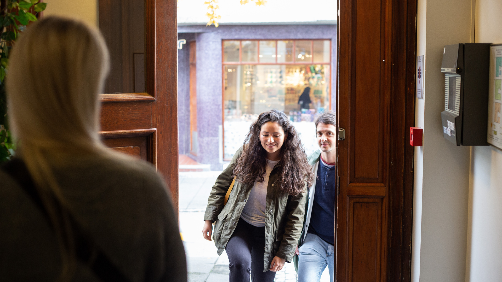 Guests entering Center Hotels Skjaldbreid in Reykjavik through a wooden front door, greeted by a hotel staff member inside.