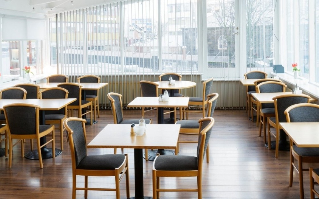 Bright breakfast area at Center Hotels Skjaldbreid in Reykjavik, with wooden floors, modern seating, and large windows offering city views.