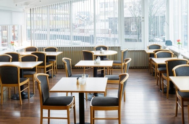 Bright breakfast area at Center Hotels Skjaldbreid in Reykjavik, with wooden floors, modern seating, and large windows offering city views.