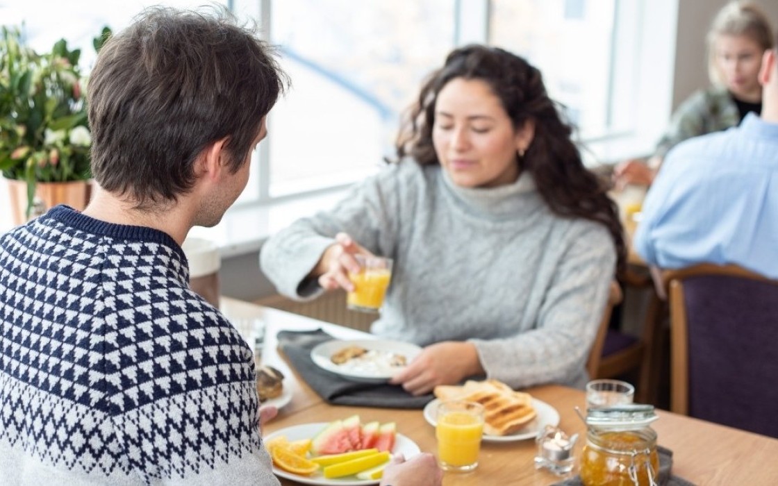 Guests enjoying breakfast at Center Hotels Skjaldbreid in Reykjavik, with fresh fruit, toast, juice, and natural light from large windows.
