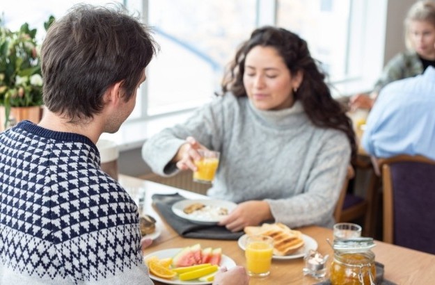 Guests enjoying breakfast at Center Hotels Skjaldbreid in Reykjavik, with fresh fruit, toast, juice, and natural light from large windows.