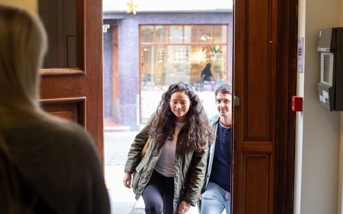 Guests entering Center Hotels Skjaldbreid in Reykjavik through a wooden front door, greeted by a hotel staff member inside.