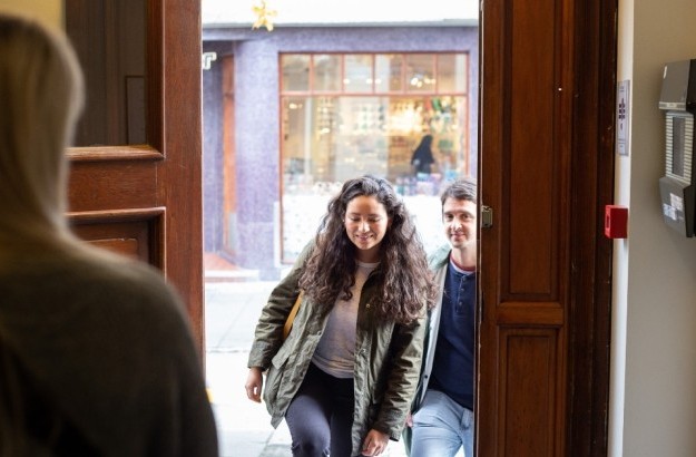 Guests entering Center Hotels Skjaldbreid in Reykjavik through a wooden front door, greeted by a hotel staff member inside.