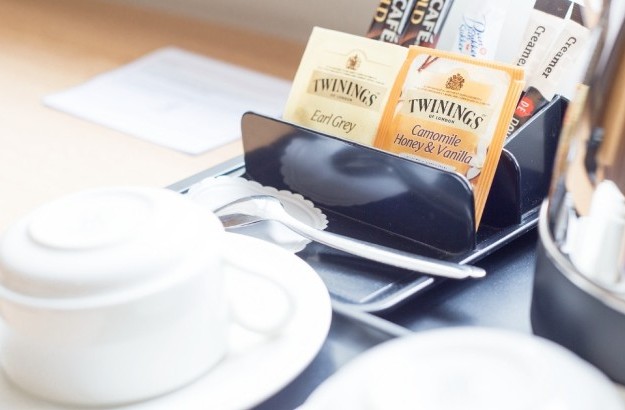 Tea and coffee setup in a standard single room at Center Hotels Skjaldbreid, with Twinings tea, instant coffee, ceramic cups, and kettle on a wooden desk.