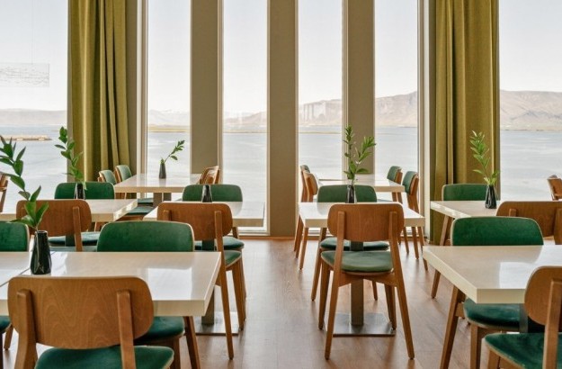 An overview of Sky bar located at Center Hotels Arnarhvoll in Reykjavik with view over the mountains, harbor, and Harpa Concert Hall.