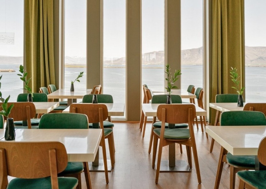 An overview of Sky bar located at Center Hotels Arnarhvoll in Reykjavik with view over the mountains, harbor, and Harpa Concert Hall.