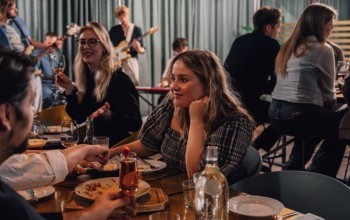 People enjoying food and drinks at Jorgensen Kitchen & Bar in Reykjavik with live music played by a band in the background.