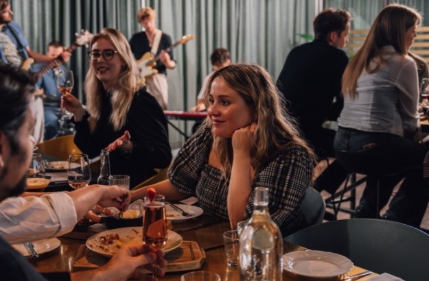 People enjoying food and drinks at Jorgensen Kitchen & Bar in Reykjavik with live music played by a band in the background.