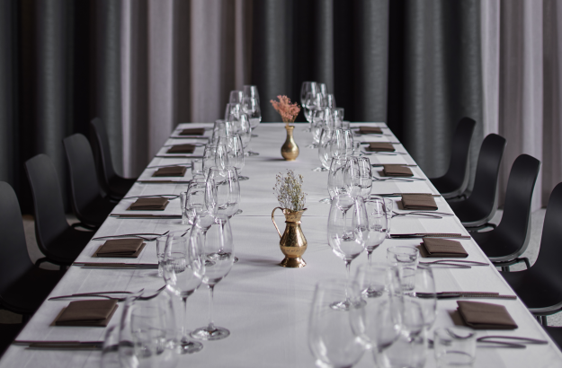 One long table set up with a white cloth, napkins and cutlery in a beautiful setting at Grandi restaurant. Set up for a group in venue style