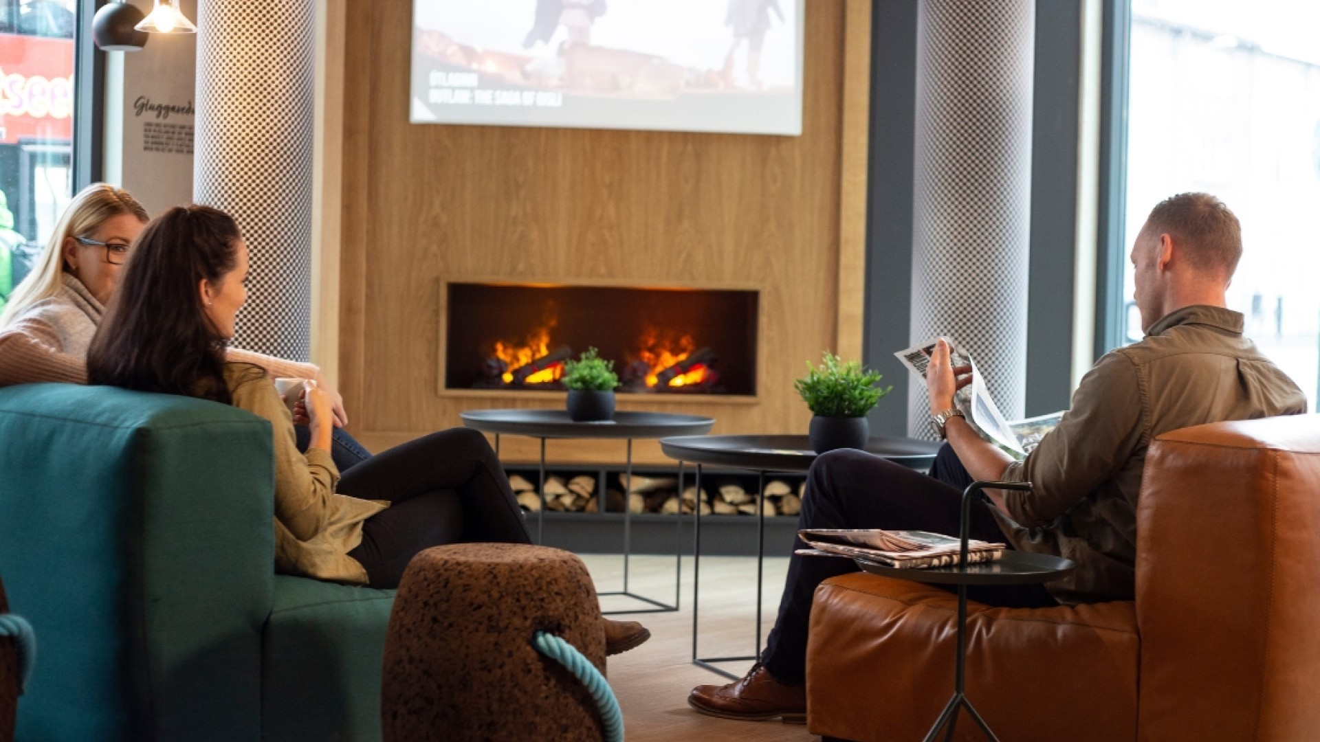 People sitting in the lounge of Center Hotels Laugavegur in Reykjavik reading a newspaper and enjoying a cup of coffee.