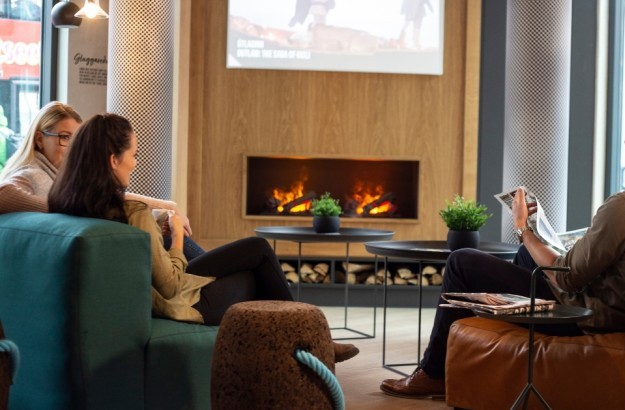 People sitting in the lounge of Center Hotels Laugavegur in Reykjavik reading a newspaper and enjoying a cup of coffee.