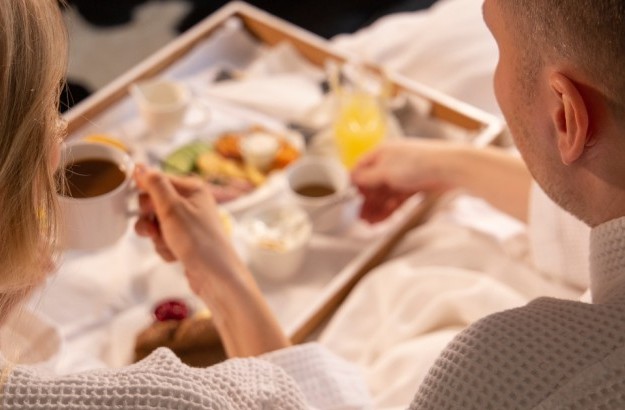 A couple enjoying coffee and breakfast plates in bed at Thingholt by Center Hotels in Iceland.