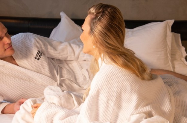 A couple in bathrobes in bed at Thingholt by Center Hotels in Reykjavik Iceland.