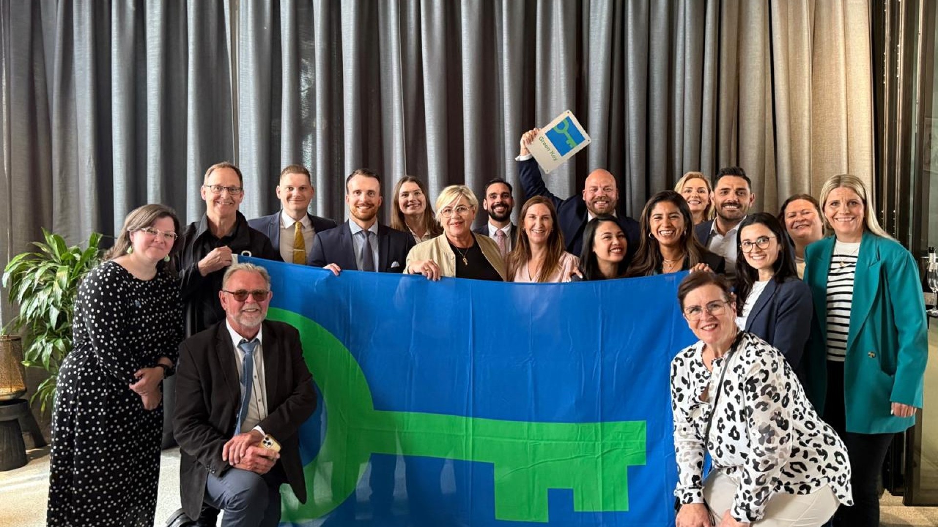 People standing together behind a large green key flag holding another smaller green key flag in Center Hotels Reykjavik Iceland