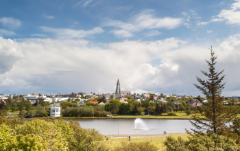 Panoramic view of Reykjavík with Hallgrímskirkja church, lake, and skyline under a bright sky