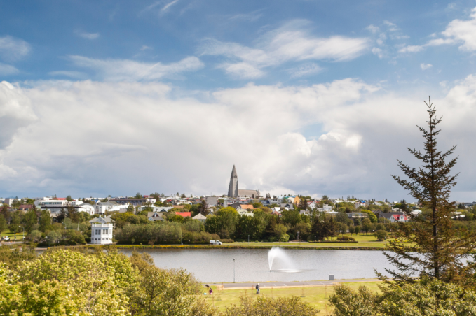 Panoramic view of Reykjavík with Hallgrímskirkja church, lake, and skyline under a bright sky