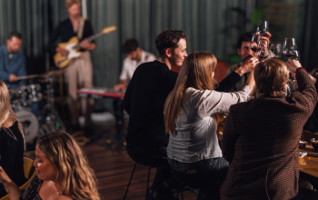 People enjoying food and drinks at Jörgensen kitchen and bar while a live band plays music in the background.