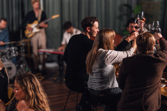 People enjoying food and drinks at Jörgensen kitchen and bar while a live band plays music in the background.