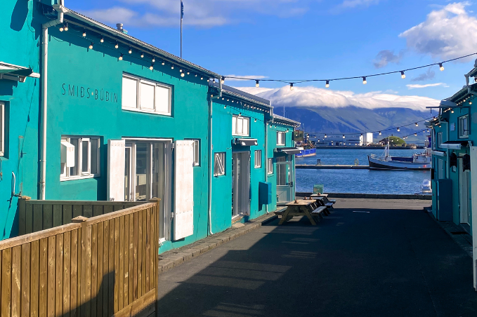 Bright turquoise houses by Reykjavík harbor with mountain views in the background