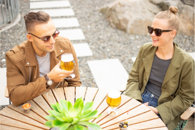 Couple enjoying drinks outdoors at a café terrace in Reykjavík on a sunny day