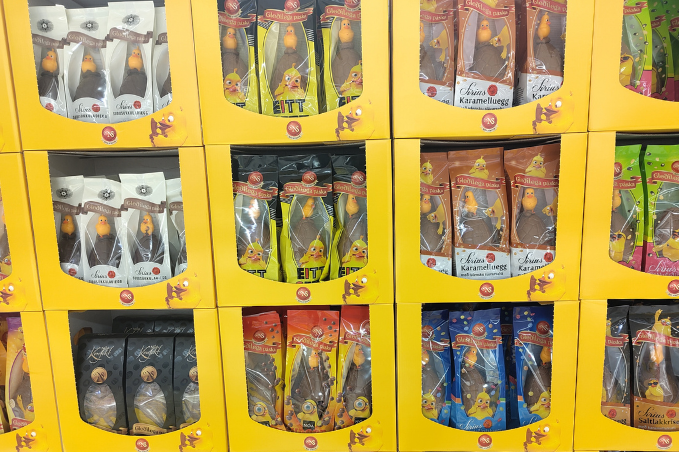 Colorful display of Icelandic Easter chocolate eggs and candy packages in bright yellow boxes inside a store.