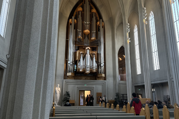 Interior view of Hallgrímskirkja church in Reykjavík featuring the large pipe organ, tall arches, and visitors inside the cathedral.