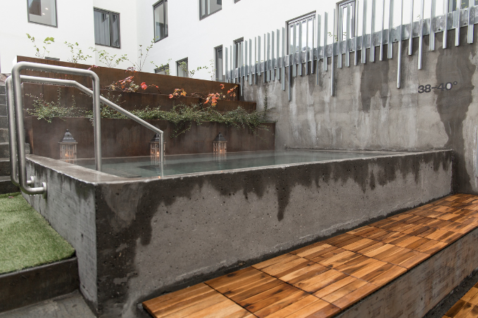 Outfoor hot tub with steam and wooden seating at Midgardur spa in Reykjavik, Iceland.