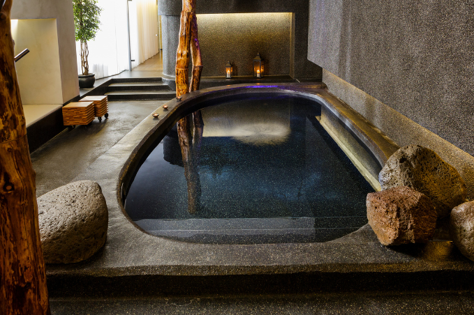 Small indoor geothermal spa pool with stone decor and warm lighting at Isafold spa in Reykjavik.