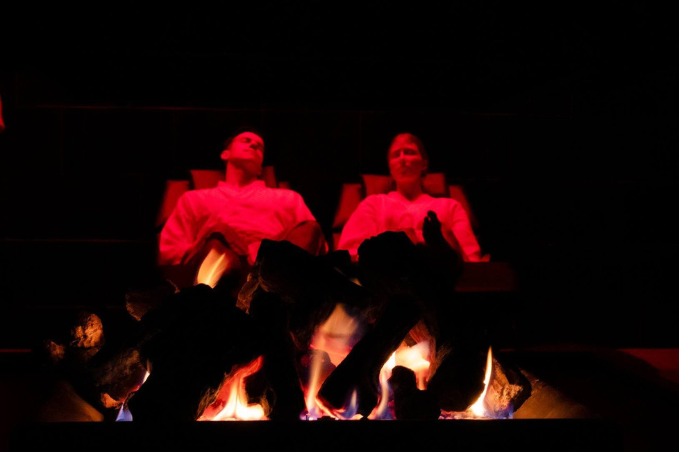 Couple relaxing by a fire in a dimly lit relaxation room at Laugar Spa in Reykjavik.