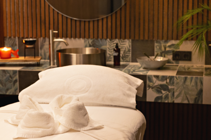 Spa treatment room with a massage table, sink, and candles in Reykjavik.