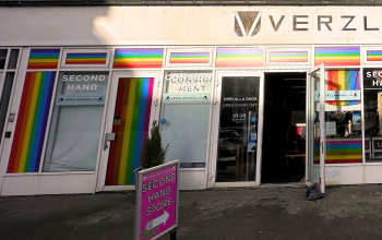Front view of Verzlanahöllin thrift shop in Reykjavík with rainbow decorations and secondhand clothes in the window.