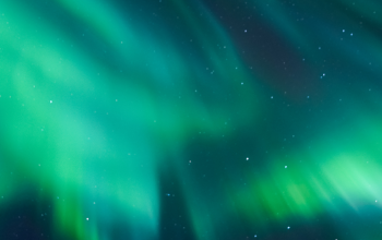 Green northern lights glowing across a starry night sky in Iceland.