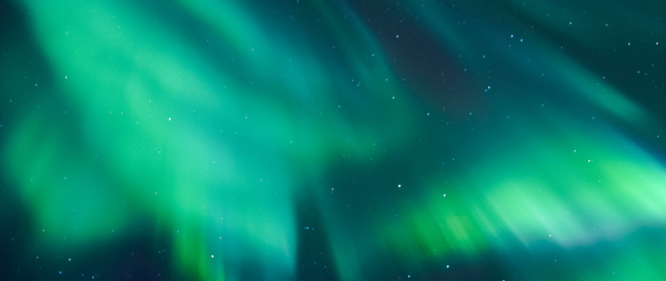 Green northern lights glowing across a starry night sky in Iceland.